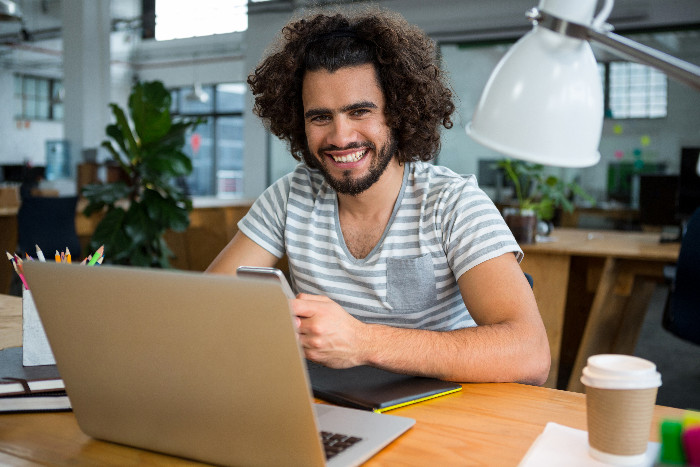 Professor smiling while assessing projects on a laptop