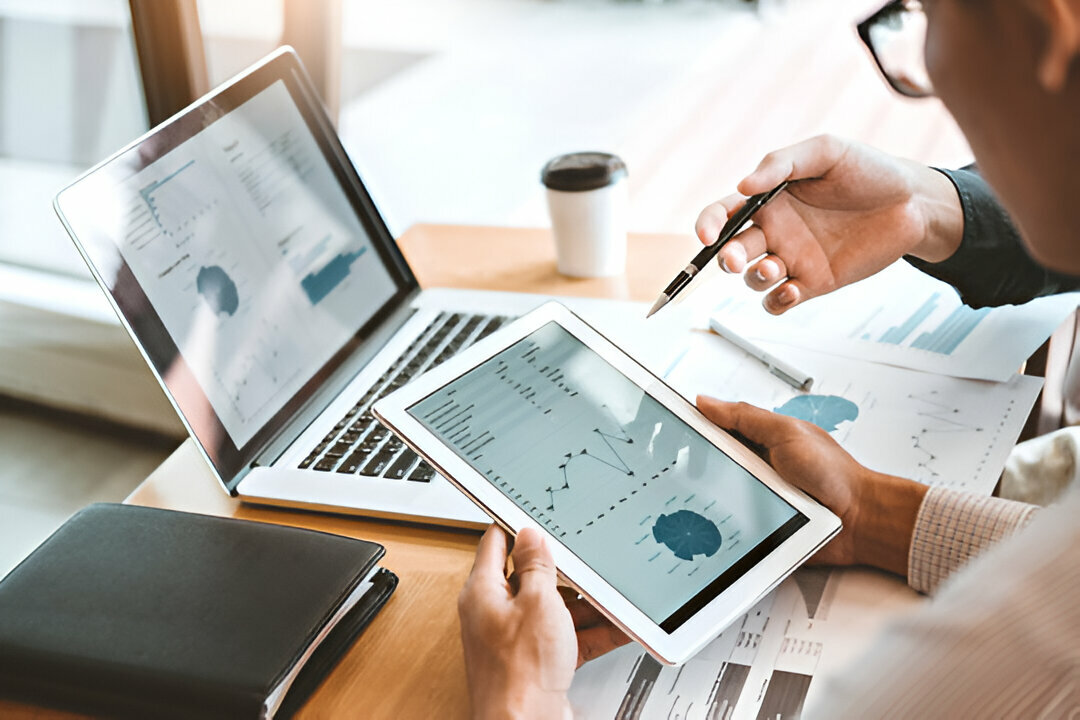 Consultants analyzing data and charts on a tablet and laptop